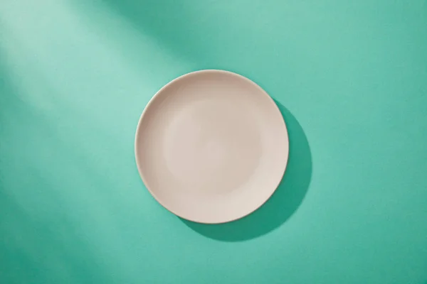 Вид сверху на пустую тарелку на бирюзовом фоне — стоковое фото