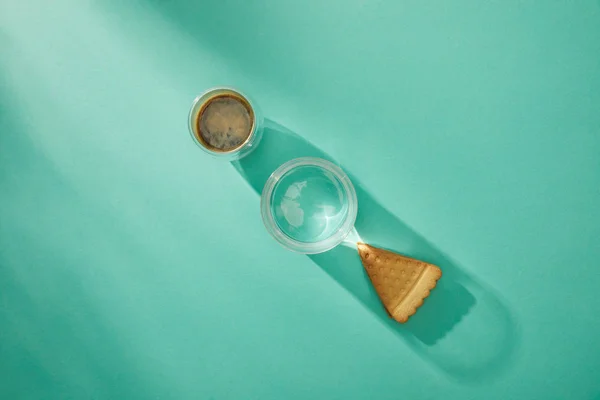 Vista dall'alto di bicchieri di acqua e caffè con gustoso biscotto su sfondo turchese — Foto stock