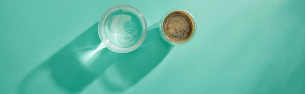 Top view of glasses of water and coffee on turquoise background, panoramic shot — Stock Photo