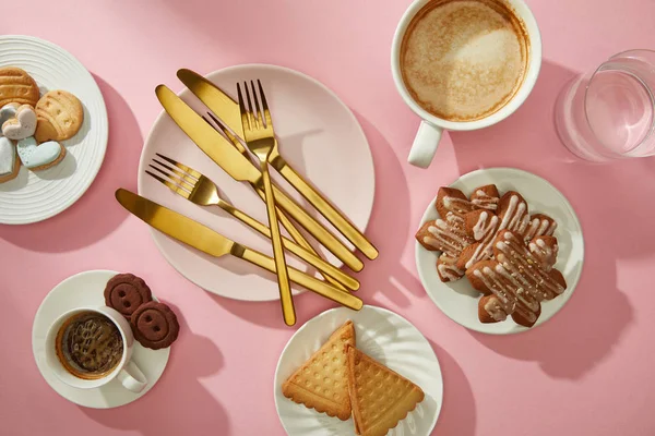 Top view of gourmet cookies and biscuits with coffee and water on pink surface — Stock Photo