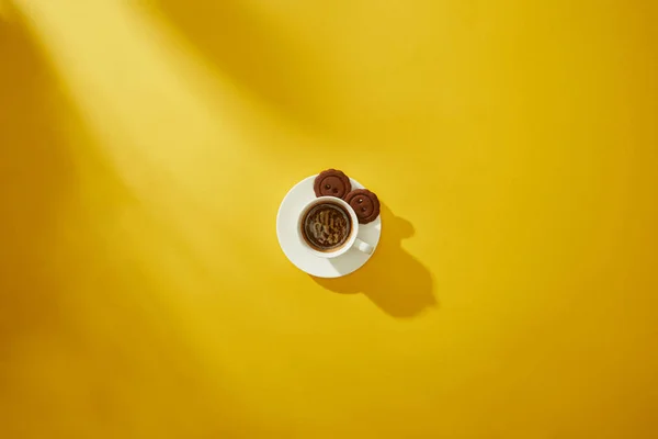 Vue du dessus des biscuits savoureux sur la soucoupe de tasse de café sur fond jaune — Photo de stock