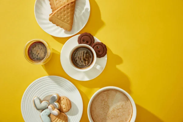 Draufsicht auf frisch gebackene Plätzchen mit Kaffee auf gelbem Hintergrund — Stockfoto