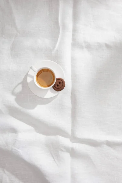 Top view of coffee cup with tasty cookie on white tablecloth with copy space — Stock Photo