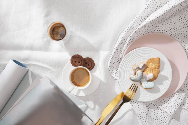 Top view of coffee with delicious cookies and magazines on white tablecloth — Stock Photo