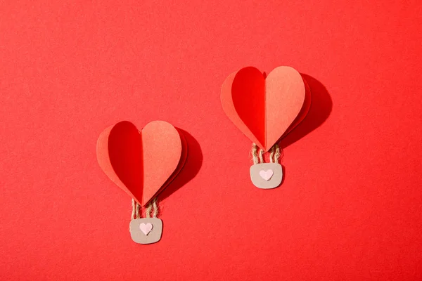 Vista superior de globos de aire en forma de corazón de papel con cerraduras sobre fondo rojo - foto de stock