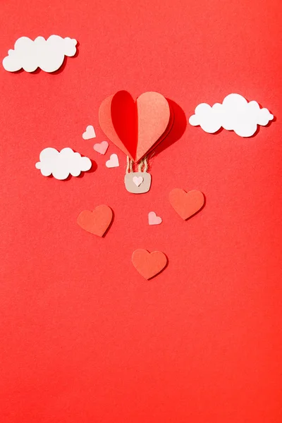 Top view of paper heart shaped air balloon in clouds on red background — Stock Photo