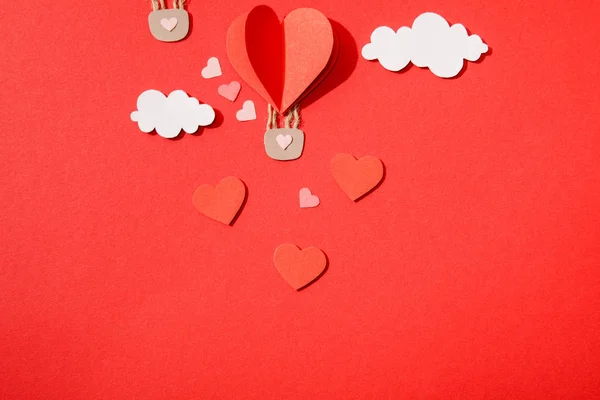 Top view of paper heart shaped air balloon in clouds on red background — Stock Photo