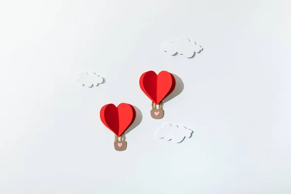 Top view of paper heart shaped air balloons in clouds on white background — Stock Photo