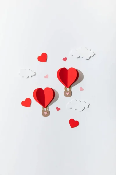 Top view of paper heart shaped air balloons in clouds on white background — Stock Photo