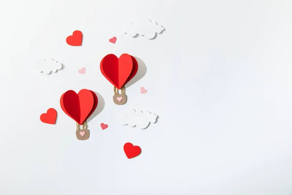 Top view of paper heart shaped air balloons in clouds on white background — Stock Photo