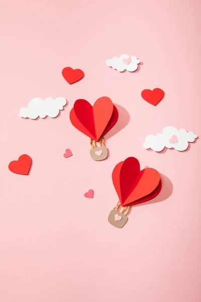 Top view of paper heart shaped air balloons in clouds on pink — Stock Photo