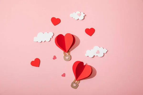 Vista dall'alto di palloncini d'aria a forma di cuore di carta in nuvole su rosa — Foto stock