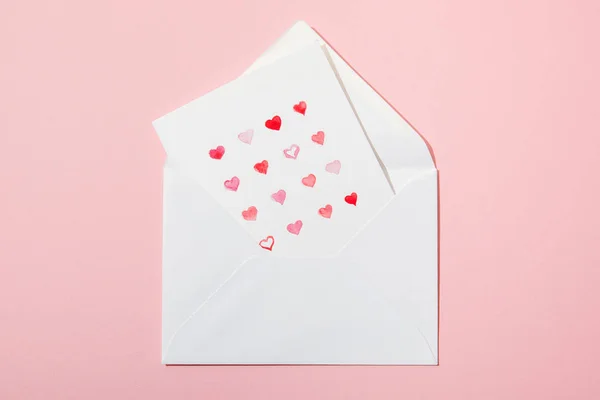 Top view of greeting card with hearts in white envelope isolated on pink — Stock Photo