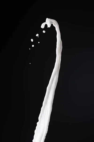 Salpicadura de leche blanca fresca con gotas aisladas en negro - foto de stock