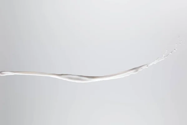 Spruzzi di latte bianco fresco puro con gocce isolate sul grigio — Foto stock