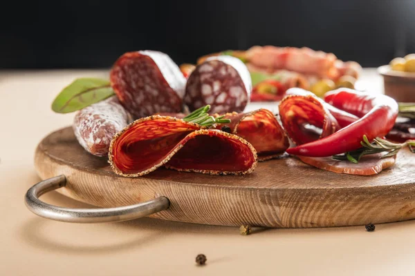 Deliciosos platos de carne servidos con romero y chile sobre tabla de madera sobre fondo beige - foto de stock