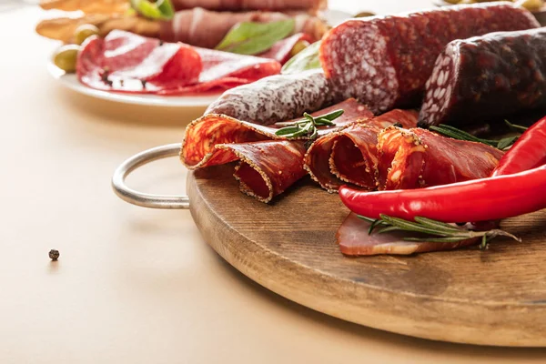 Délicieux plats de viande servis avec des olives, des épices et des bâtonnets de pain sur plaque et planche de bois sur fond beige — Photo de stock