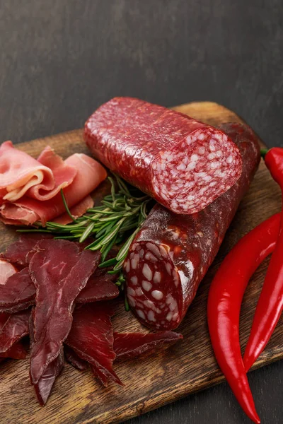 Close up view of delicious meat platter served with chili pepper and rosemary on wooden black table — Stock Photo