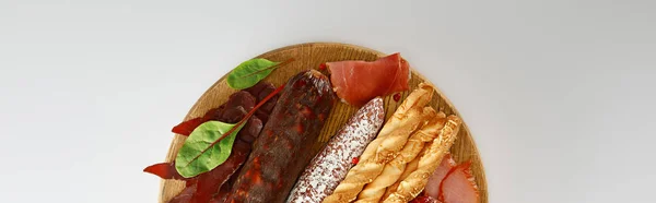 Top view of delicious meat platter served with breadsticks and herbs on board isolated on white, panoramic shot — Stock Photo