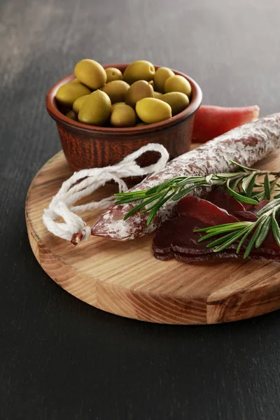 Delicious meat platter served with olives on board on black surface — Stock Photo