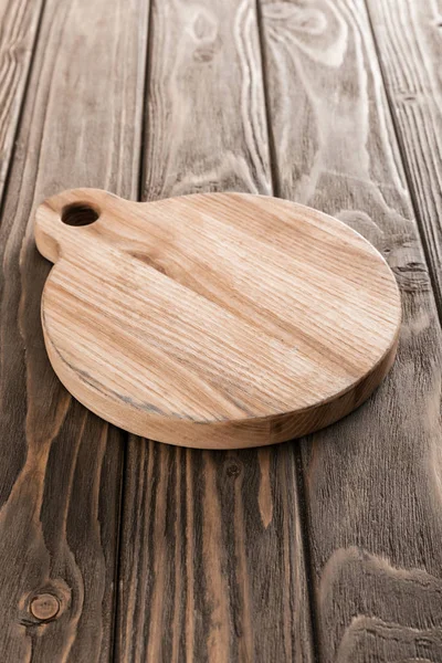 Brown empty cutting board on wooden table — Stock Photo