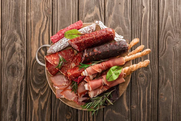 Vista dall'alto di deliziosi piatti di carne serviti con rosmarino e grissini su tavola di legno — Foto stock