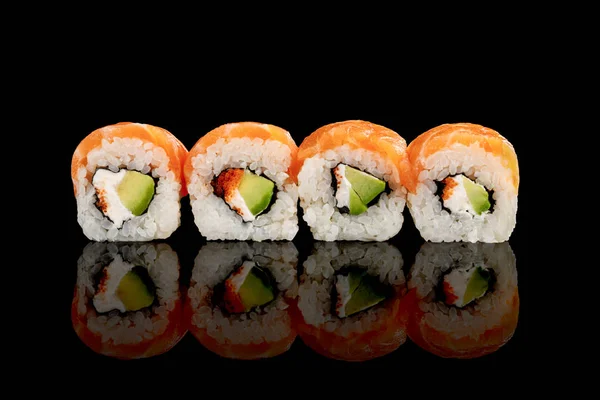 Frische köstliche Philadelphia Sushi mit Avocado, cremigem Käse, Lachs und Masago Kaviar isoliert auf schwarz — Stockfoto