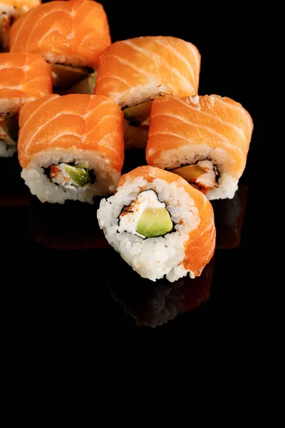 Delicious Philadelphia sushi with avocado, creamy cheese, salmon and masago caviar isolated on black — Stock Photo