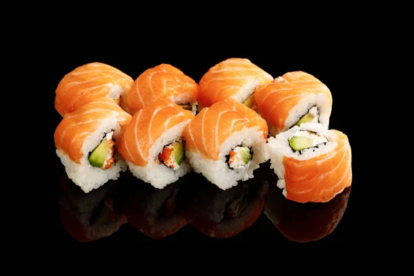 Délicieux sushi Philadelphie à l'avocat, fromage crémeux, saumon et caviar masago isolé sur noir — Photo de stock