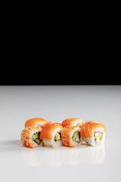 Köstliches philadelphia und california sushi mit lachs und masago kaviar auf weißer oberfläche isoliert auf schwarz — Stockfoto