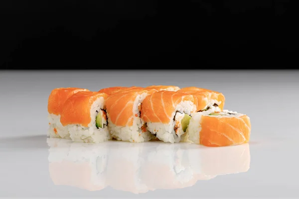 Delicious Philadelphia sushi with avocado, creamy cheese, salmon and masago caviar on white surface isolated on black — Stock Photo