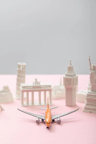Selektiver Fokus von Spielzeugflugzeugen in der Nähe kleiner Statuetten verschiedener Länder auf grau und rosa — Stockfoto