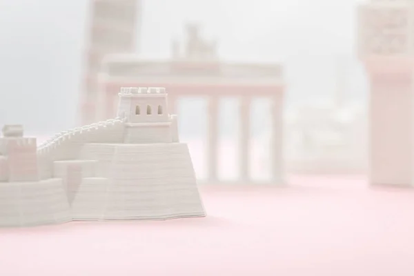 Вибірковий фокус маленької великої фігурки стіни біля статуеток на сірому і рожевому — стокове фото