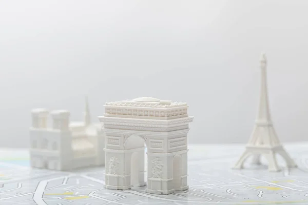 Foco selectivo de arco de triomphe cerca de pequeñas figurillas en el mapa de París aislado en gris - foto de stock