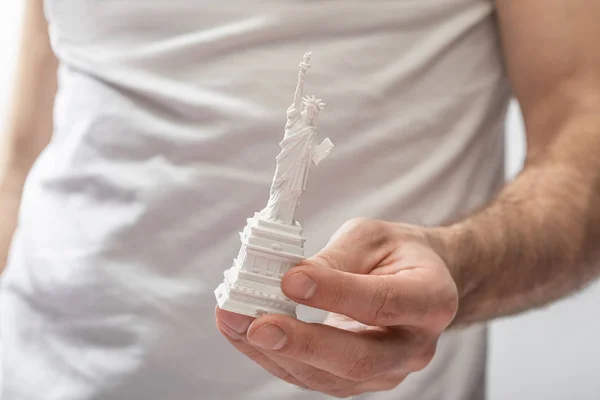 Vista ritagliata dell'uomo che tiene la statua della libertà isolata sul bianco — Foto stock
