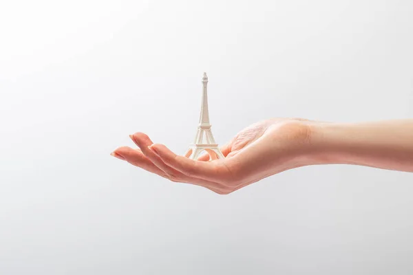 Vista cortada da mulher segurando pequena estatueta da torre eiffel isolado no branco — Fotografia de Stock