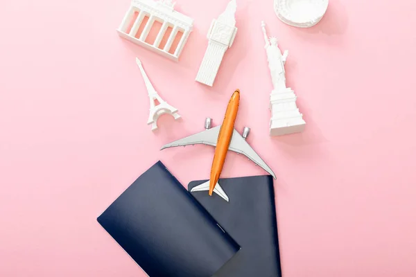 Top view of passports near toy plane and figurines from countries on pink — Stock Photo