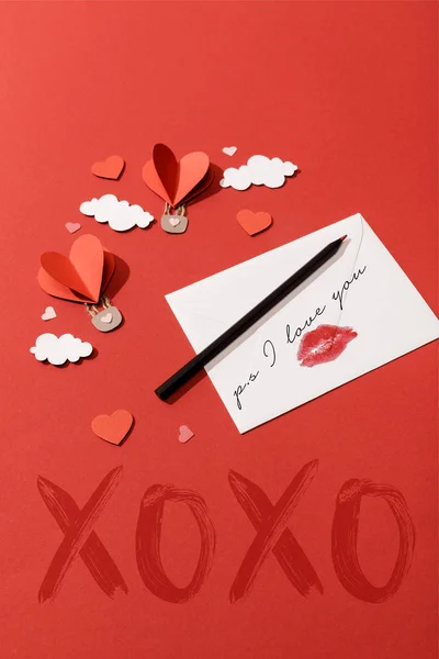 Nuvole di carta e palloncini d'aria a forma di cuore e busta con ps ti amo lettering su sfondo rosso — Foto stock