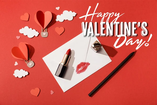 Top view of heart shaped air balloons, lipstick and pencil near envelope with lip print and happy valentines day lettering on red background — Stock Photo