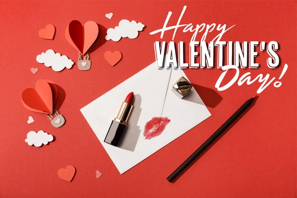 Draufsicht auf herzförmige Luftballons, Lippenstift und Bleistift in der Nähe von Briefumschlag mit Lippenprint und fröhlichem Valentinstag Schriftzug auf rotem Hintergrund — Stockfoto