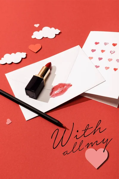 Nubes de papel y corazones, lápiz labial, tarjeta de felicitación y sobre con impresión de labios cerca con todas mis letras sobre fondo rojo - foto de stock