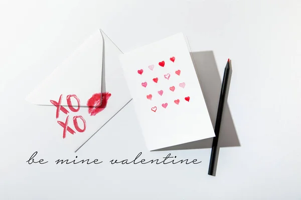 Вид зверху вітальної листівки з сердечками біля конверта з принтом для губ біля мого валентинки на білому тлі — стокове фото