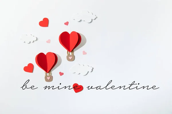 Top view of paper heart shaped air balloons in clouds near be mine valentine lettering on white background — Stock Photo