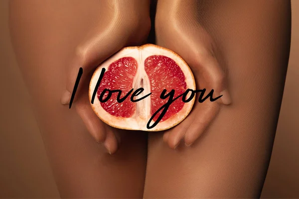 Abgeschnittene Ansicht einer Frau in Nylonstrumpfhosen, die Grapefruit halb in der Nähe hält Ich liebe dich Schriftzug auf braun — Stockfoto