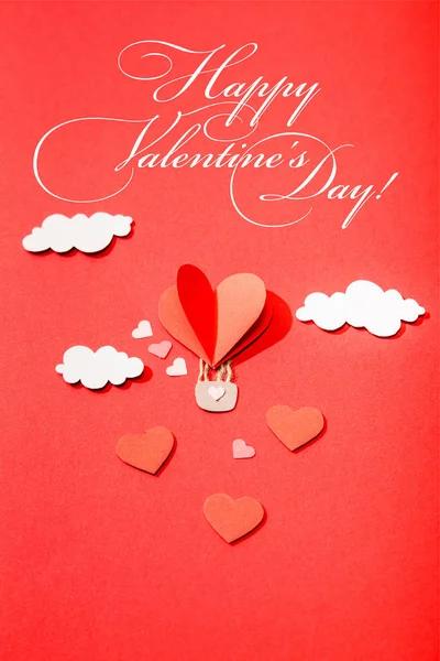 Top view of paper heart shaped air balloon in clouds near happy valentines day lettering on red background — Stock Photo