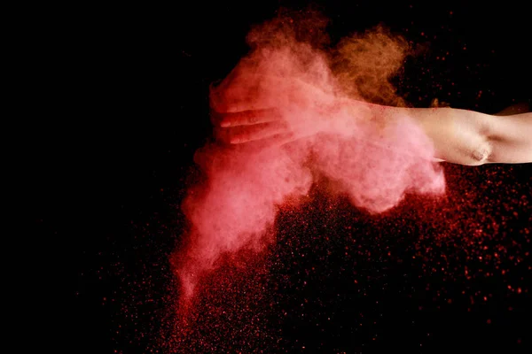 Female hand in pink colorful holi paint explosion on black background — Stock Photo