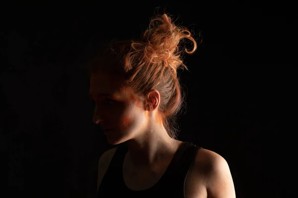 Жінка з помаранчевою барвистою фарбою Холі на обличчі ізольована на чорному — стокове фото