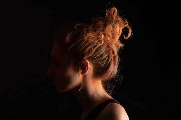 Profile of woman with orange colorful holi paint powder on face isolated on black — Stock Photo