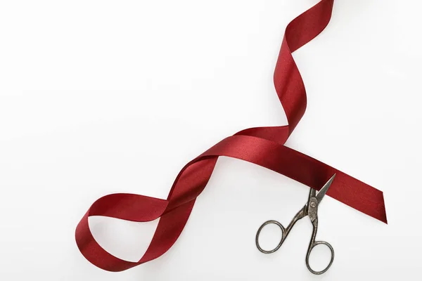 Top view of satin burgundy decorative curved ribbon with scissors isolated on white — Stock Photo