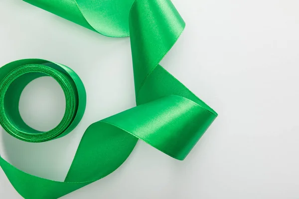 Vue du dessus du ruban courbé décoratif vert satiné sur blanc — Photo de stock